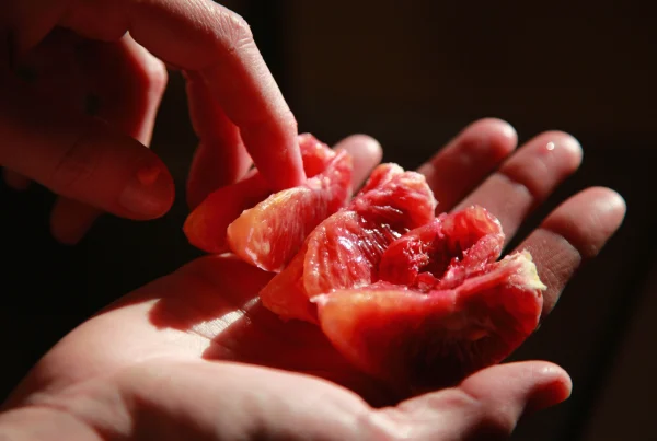Manos acariciando fruta simbólica para representar el masaje erótico sensorial y terapéutico en Bliss Barcelona.