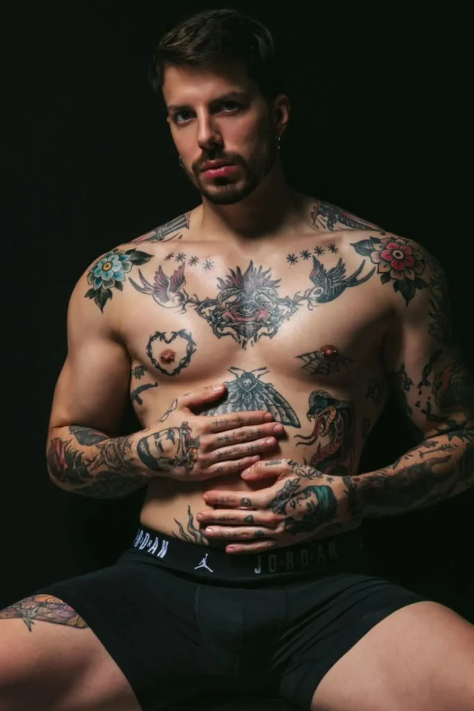 Enea, masajista erótico de Bliss Barcelona, mostrando su torso tatuado en ropa interior con mirada penetrante